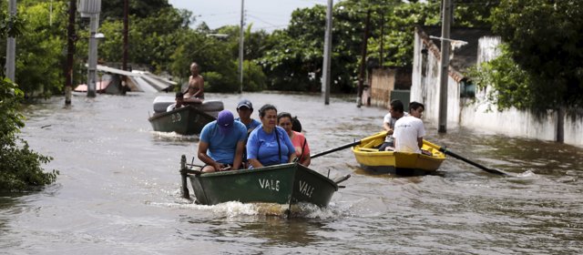 People travel on a boat near flood-affected houses in Asuncion, December 27, 201