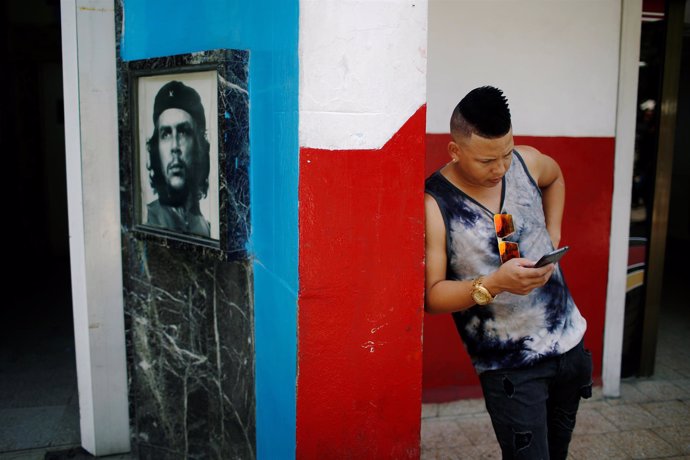 Joven cubano navegando en Internet junto a una imagen del Che
