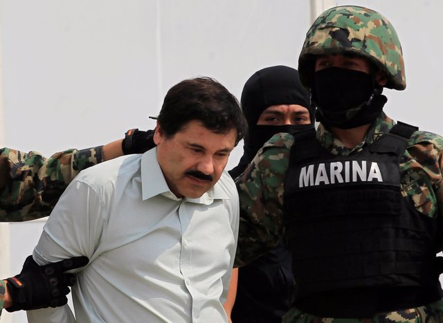 Joaquin "El Chapo" Guzman (L) is escorted by soldiers during a presentation at t