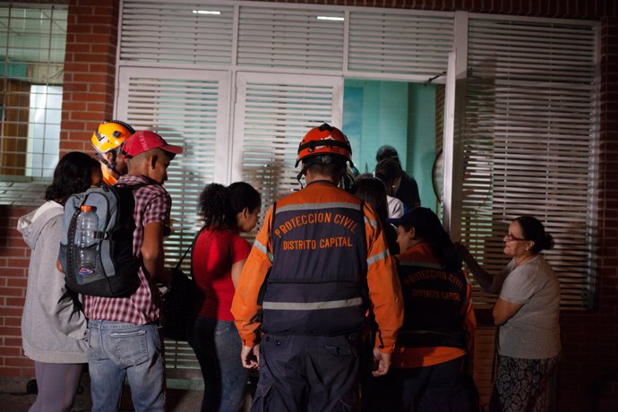 Venezuelan Civil Protection members help evacuees return to the building of the 
