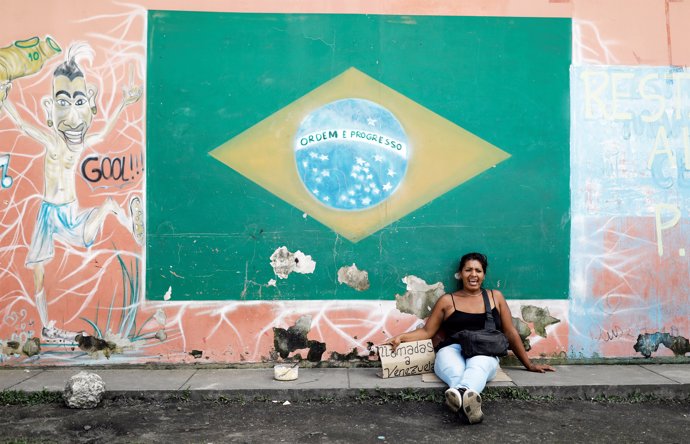 Una mujer venezolana junto a la bandera de Brasil en Roraima