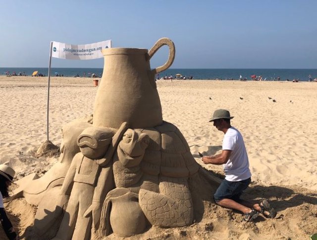 Escultura de arena en la playa para campaña de OCU