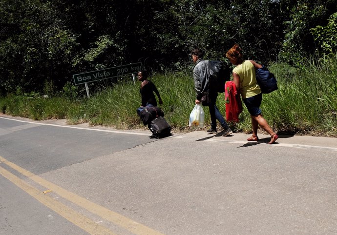 Venezuelans walk and attempt to hitchhike toward Boa Vista city, after they obta