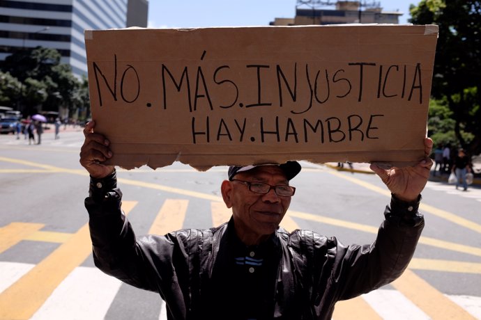 A man holds a placard that reads "No more injustice. There is hunger" during a r