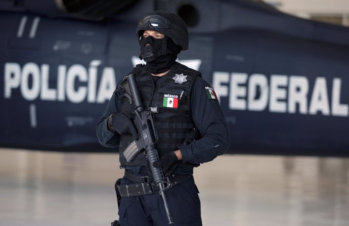 A Mexican federal policeman stand guards during a presentation of four suspected