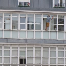 Hombre que limpia los cristales asomado a la ventana en Santander 
