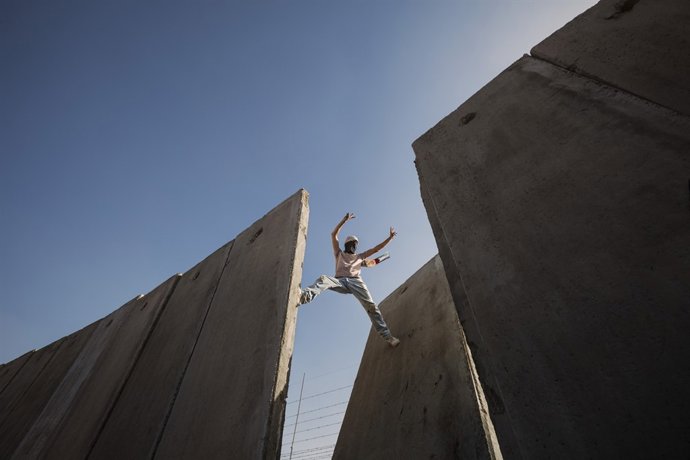 Foto d'un palestí sobre una bretxa del mur de Cisjordània de Bernat Armangué