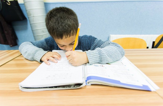 Un niño escribe en un libro de texto