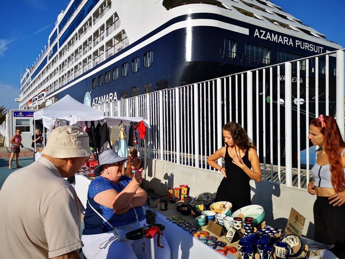 Unos cruceristas visitan un puesto de artesanía en el desembarque