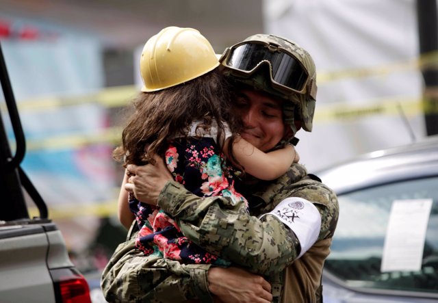 A girl hugs a Mexican marine officer as she offers hugs to people near the site 