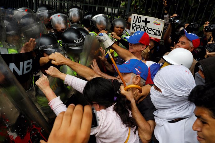 Opposition supporters confront riot security forces while rallying against Presi