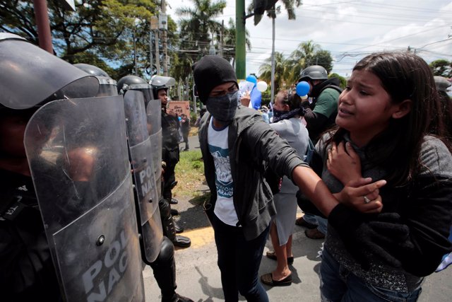 Manifestante frente a policía antidisturbios en Managua.