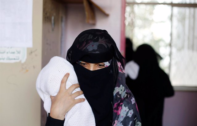 Una mujer con su hijo malnutrido en un hospital de Saná