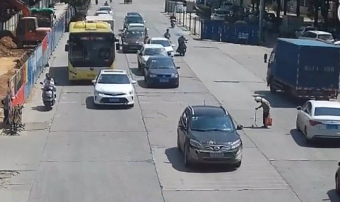 Anciana trata de cruzar una calle con mucho tráfico