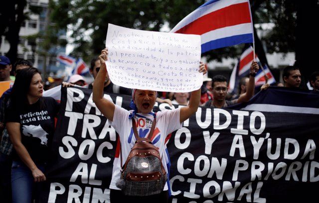 A demonstrator holds a poster against government policies on migration during a 