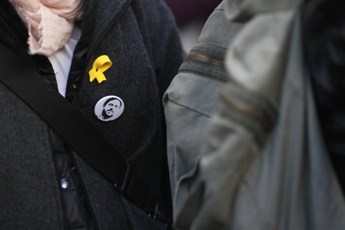 Persona con el lazo amarillo y chapa con la cara de Junqueras