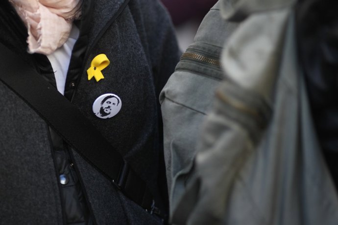 Persona amb el llaç groc i xapa amb la cara de Junqueras