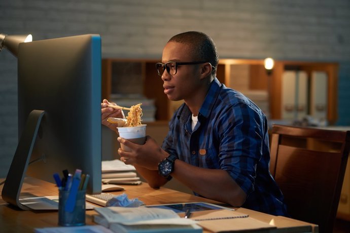 Trabajador comiendo ante un ordenador