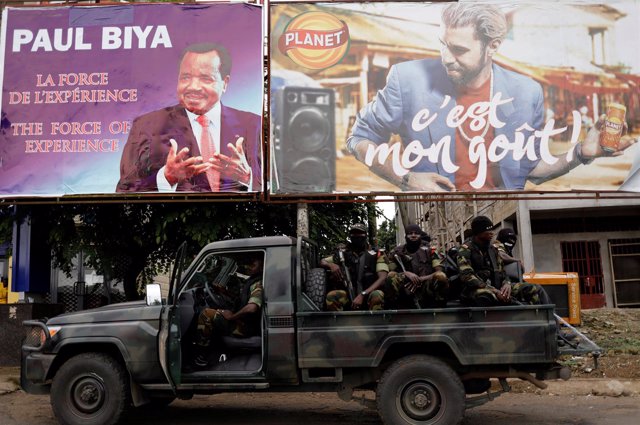 Soldados del Batallón de Intervención Rápida ante cartel electoral en Buea