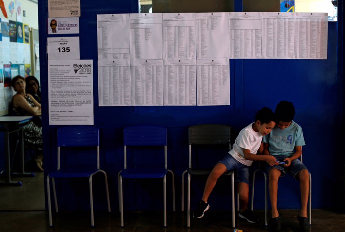 Children sit at a polling station during the presidential election in Brasilia, 