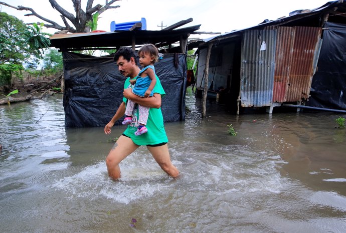 A local resident holds his daughter, as he walks through floodwaters after heavy