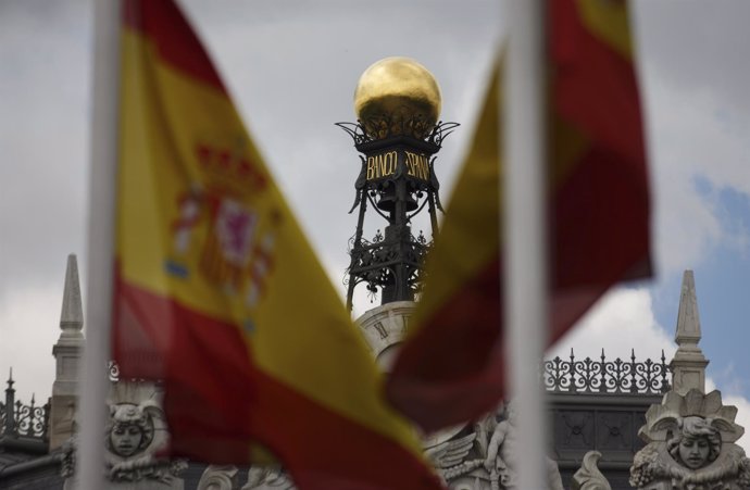 The dome of the Bank of Spain is seen between Spanish flags in central Madrid Ju