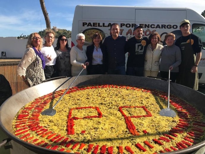 Bonig en Oliva junto a la paella con el logo del PP