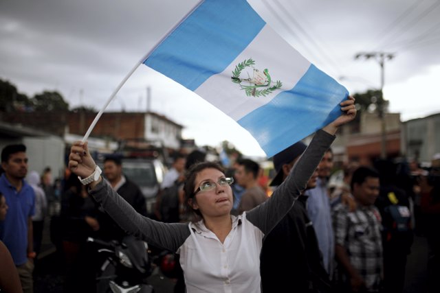 A woman holds a Guatemalan flag and celebrates as Guatemala's former President O