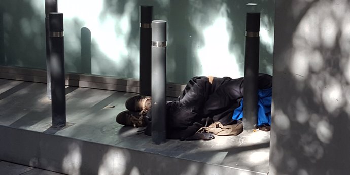 Una persona durmiendo en la calle entre bolardos