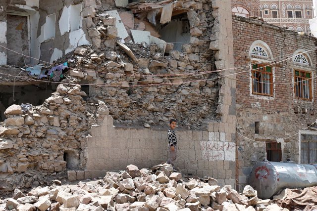 Un niño entre los escombros de una casa destruida en un bombardeo en Saná