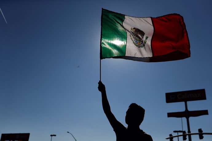 A demonstrator waves a Mexican flag, during a protest against migrants who are p
