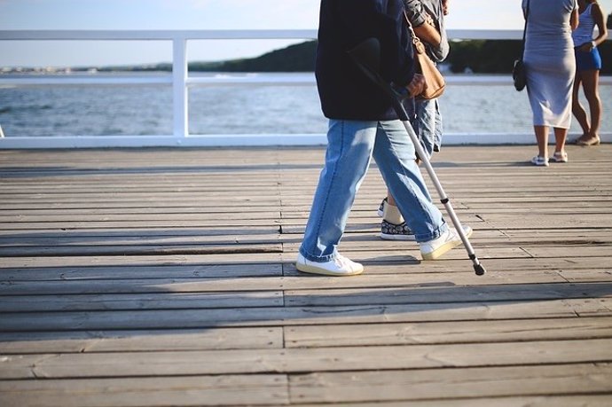 Mujer anda con una muleta, osteoporosis