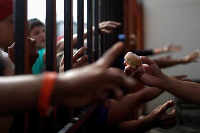 Migrants, part of a caravan traveling en route to the United States, try to get