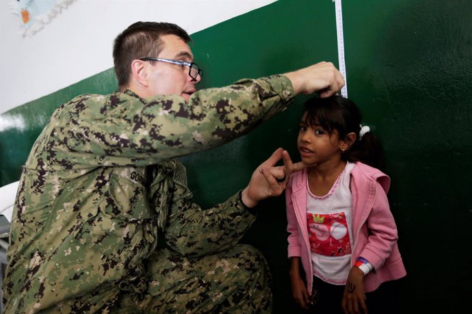 Una niña venezolana recibe la atención de un miembro del buque USNS Comfort