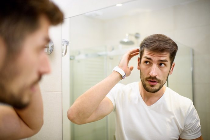 Hombre con barba mirando al espejo en el baño