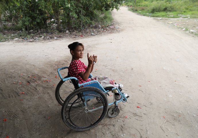Catherine Ramos, 15, sits in a wheelchair in a street in San Pedro Sula, Hondura