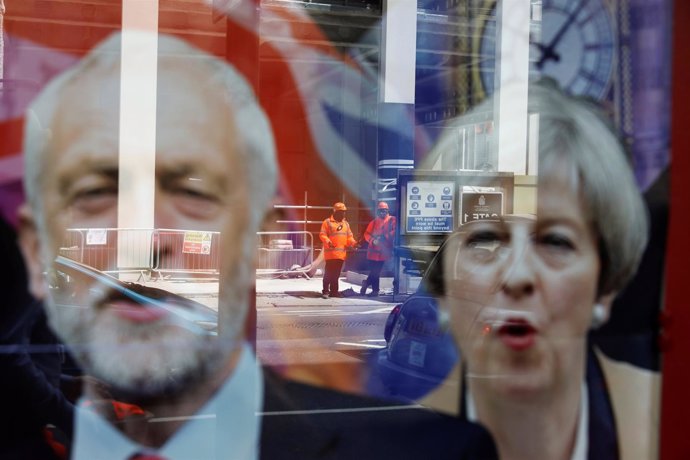 Imagen de Theresa May y Jeremy Corbyn reflejada en un cristal