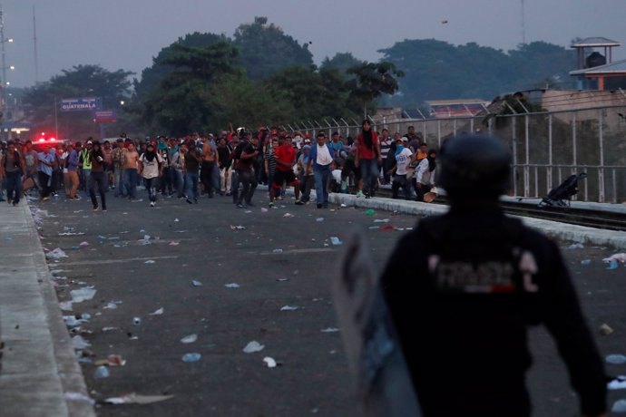 Migrantes tratando de cruzar hasta México frente a policía
