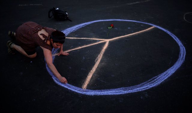 Una mujer dibuja el símbolo de la paz en el suelo