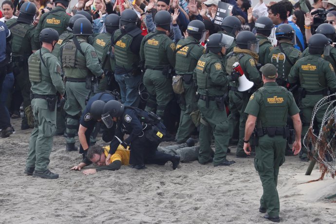 Police officers detain a man during a gathering in support of the migrant carava