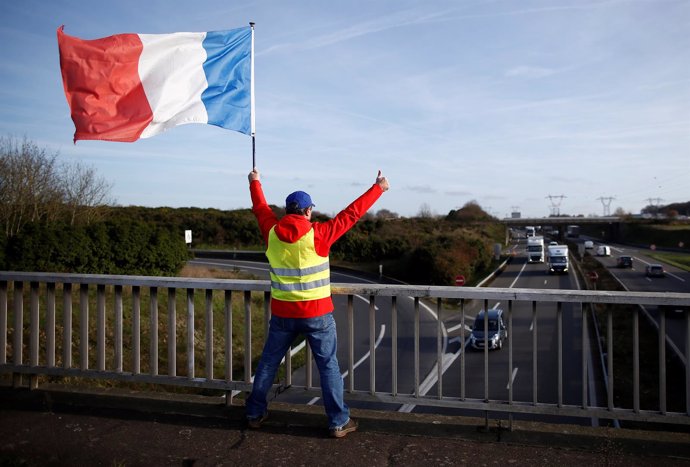 Un hombre con chaleco amarillo y una bandera francesa en Bouguenais
