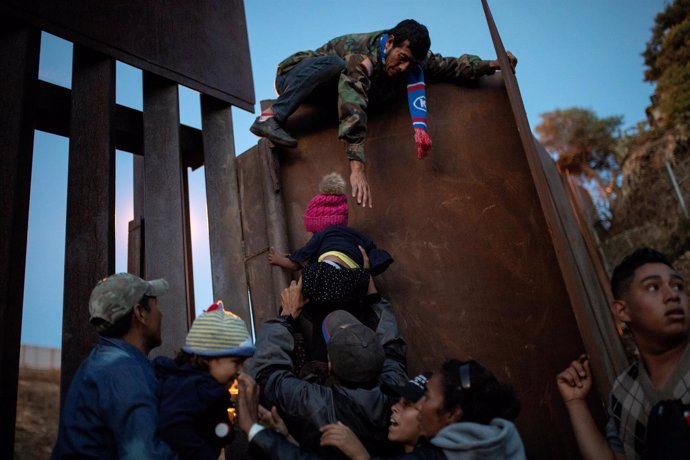 Migrantes tratan de saltar la valla en la frontera entre México y EEUU