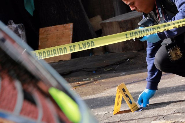 A forensic technician works at a crime scene where two men were gunned down by u