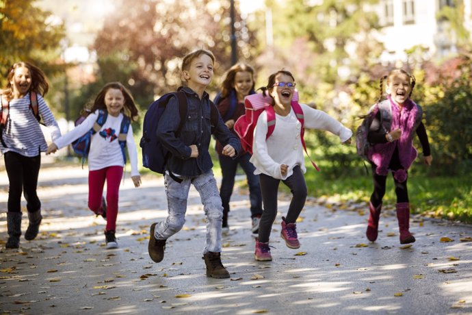 Niños, escolares con mochila, corriendo, jugando, yendo al colegio