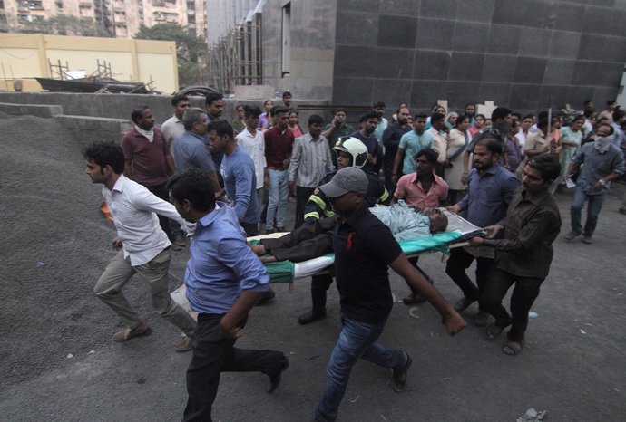 Varias personas llevan el cuerpo de uno de los heridos en un incendio en Bombay