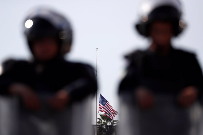 A U.S. Flag is lowered in the U.S. Consulate as Mexican riot police officers sta