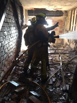 Los bomberos trabajan en la habitación que ha quedado calcinada
