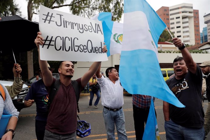 A demonstrator (L) holds a sign as he protests against Guatemalan President Jimm