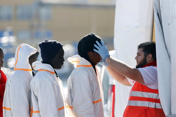 Un miembro de Cruz Roja atiende a inmigrantes llegados al puerto de Málaga