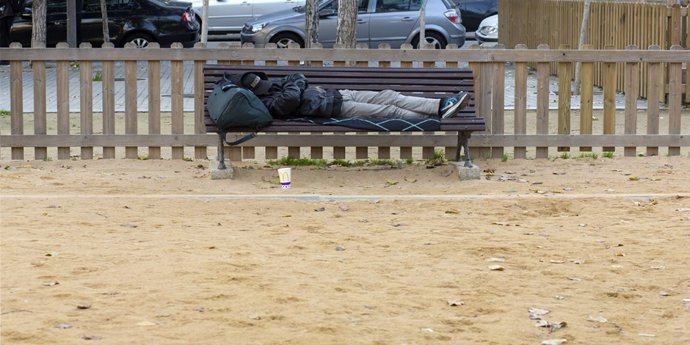 Una persona duerme en un banco en Barcelona